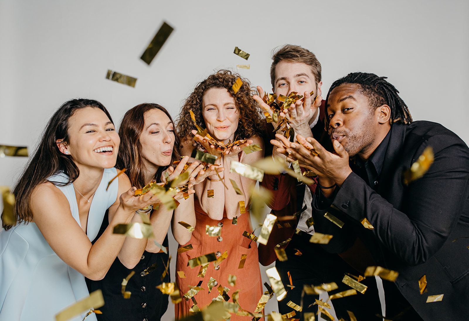 A group of people are blowing confetti towards the camera.