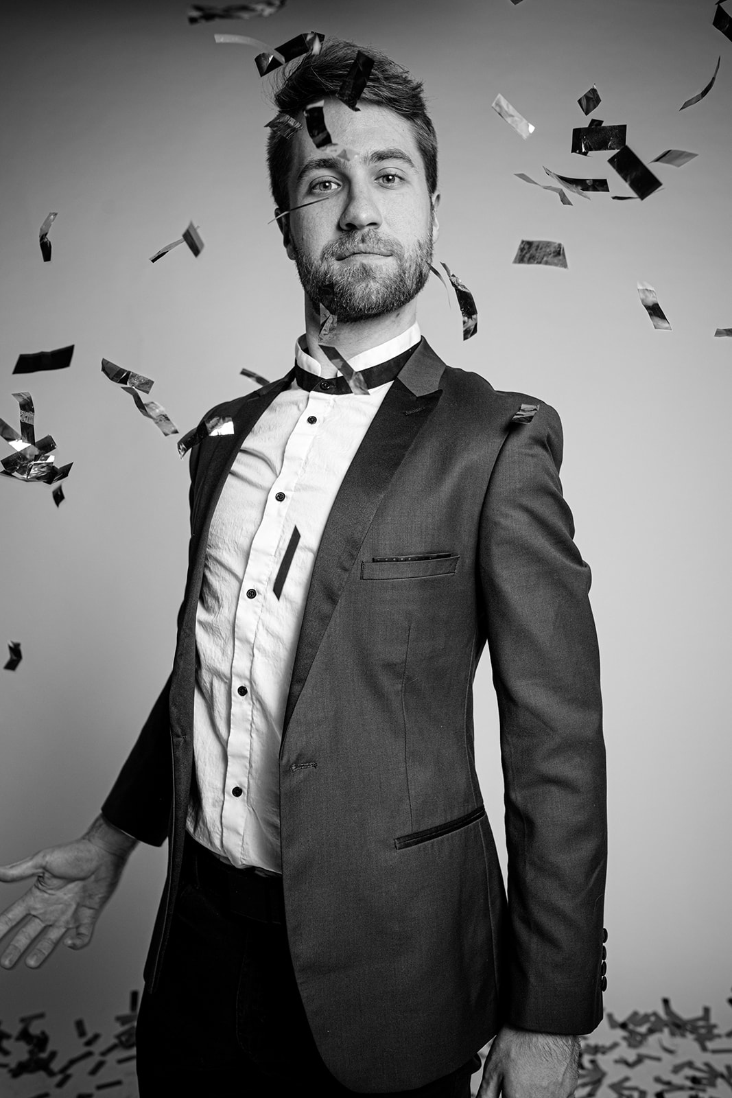 A man stands before the photobooth. Confetti falls in front of him.