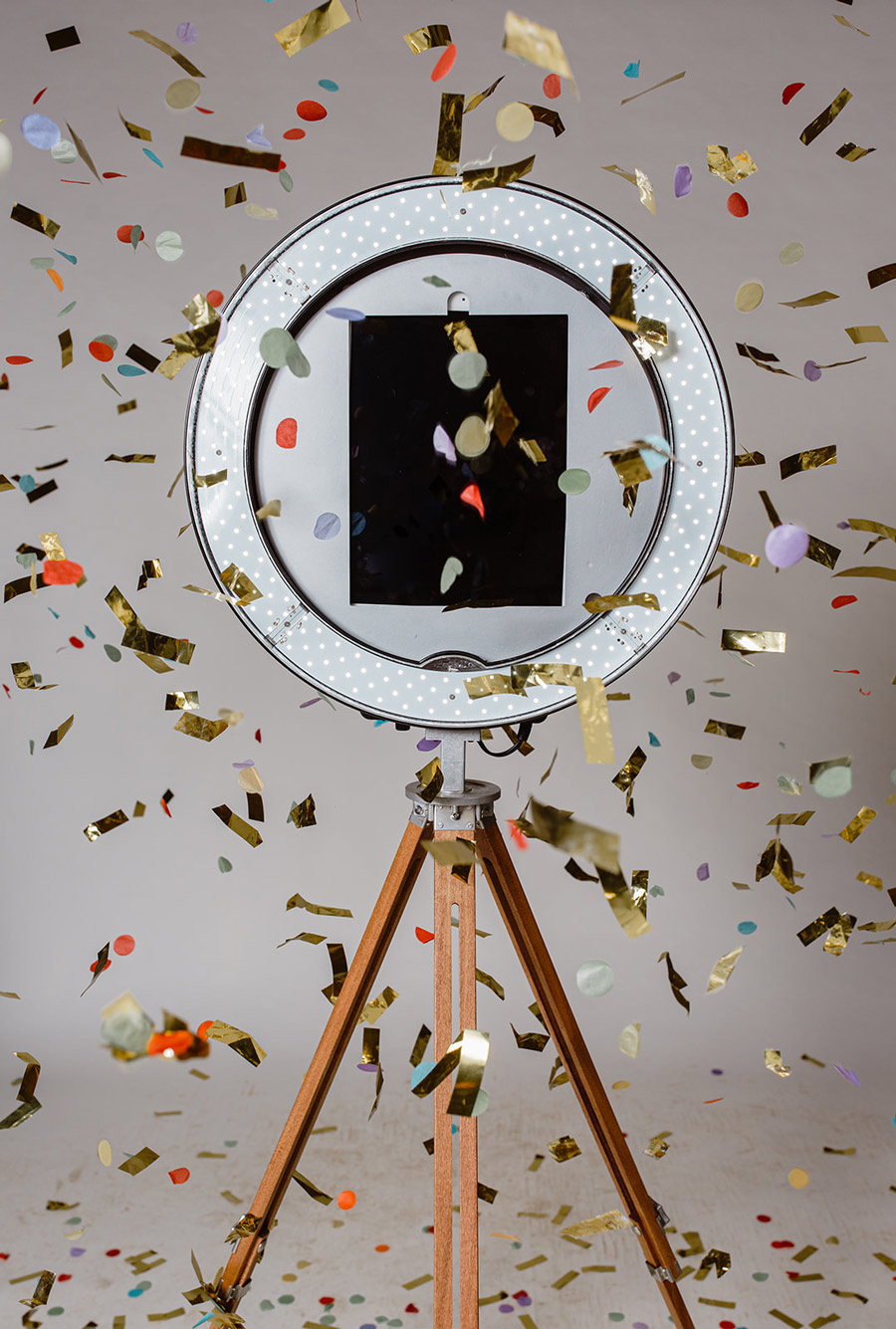 The gifyyy photobooth stands opposite the camera. Confetti drifts down through the air in front of it.